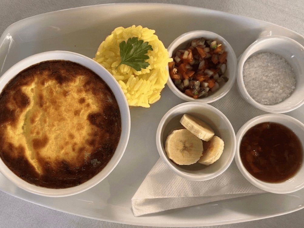 Bobotie sudafricano servido con arroz basmati amarillo, rodajas de plátano, chutney de albaricoque y coco rallado.